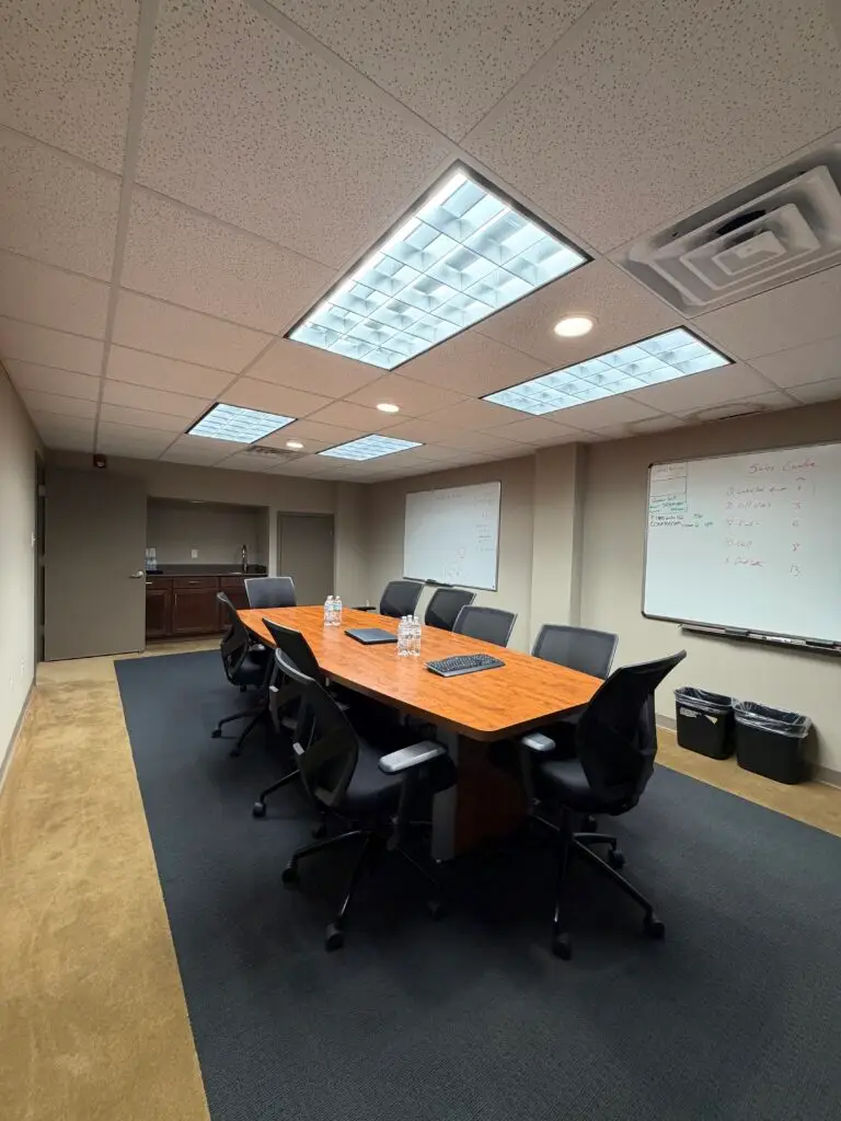 Boardroom Suites conference room in Metairie showing 10-seat meeting table, whiteboards and kitchenette area