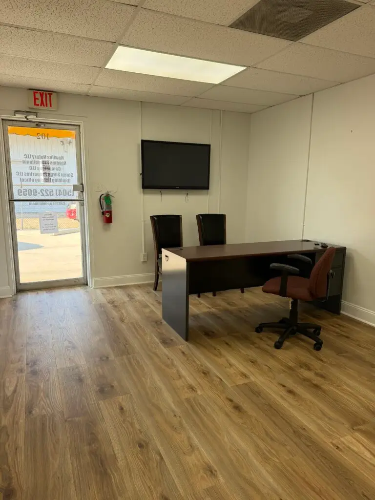 Suite 102 first-floor office in Metairie showing furnished workspace, guest seating and wall TV or monitor