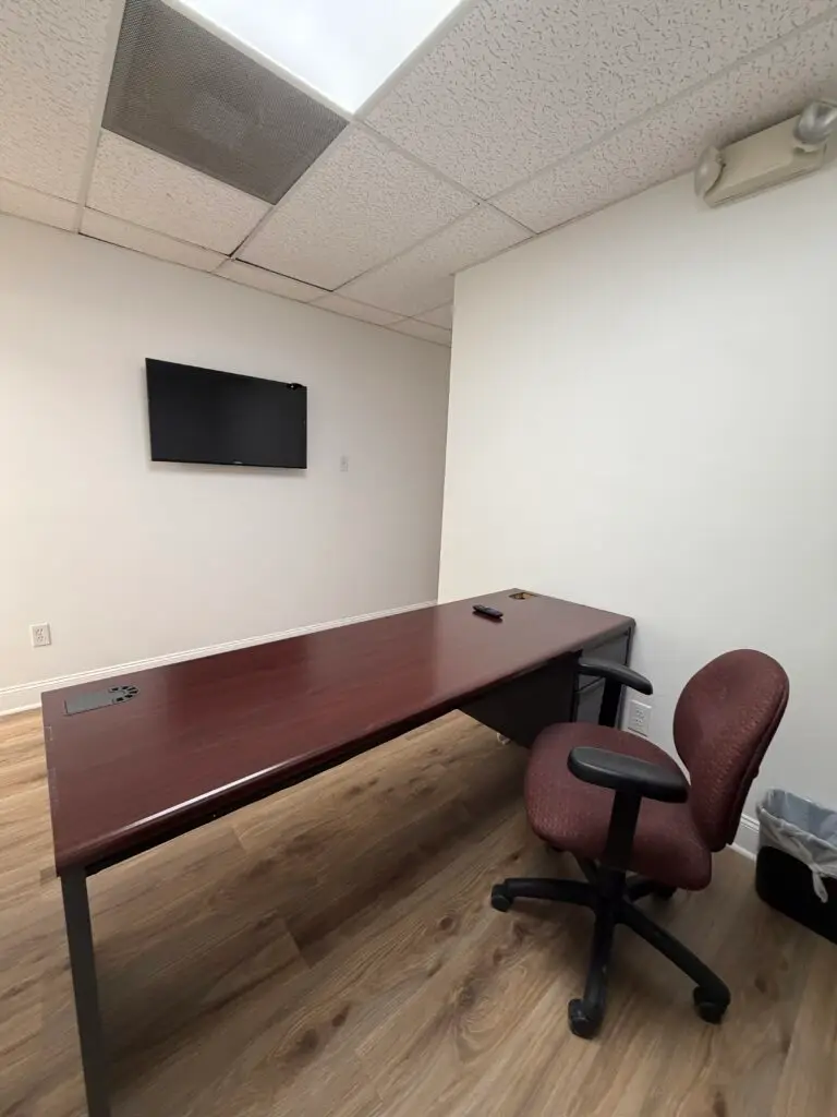 Suite 102 furnished private office in Metairie with desk, office chair and wall-mounted monitor