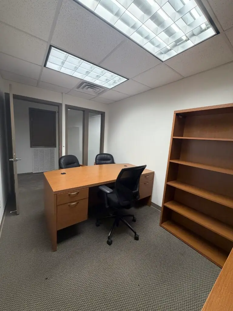 Boardroom Suites Suite 203 private office in Metairie showing desk, guest chairs and open shelving
